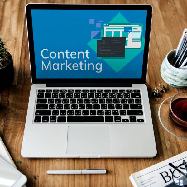 Laptop on a wooden desk displaying _Content Marketing_ with plants, stationery, and tea Laptop on a wooden desk displaying _Content Marketing_ with plants, stationery, and tea
