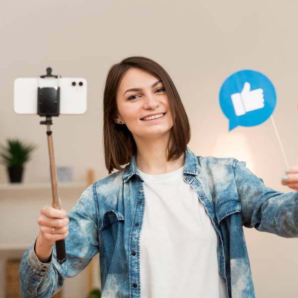 Person holding like and heart social media signs in front of a smartphone on a tripod Person holding like and heart social media signs in front of a smartphone on a tripod