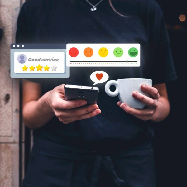 Person in black with a phone and coffee cup, digital feedback icons above Person in black with a phone and coffee cup, digital feedback icons above